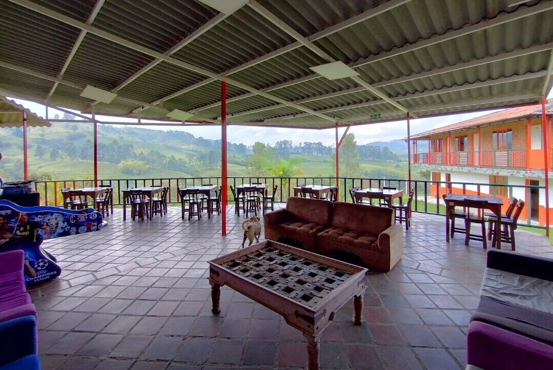 Una veranda esterna con tavoli e sedie, un divano e un tavolino decorativo.