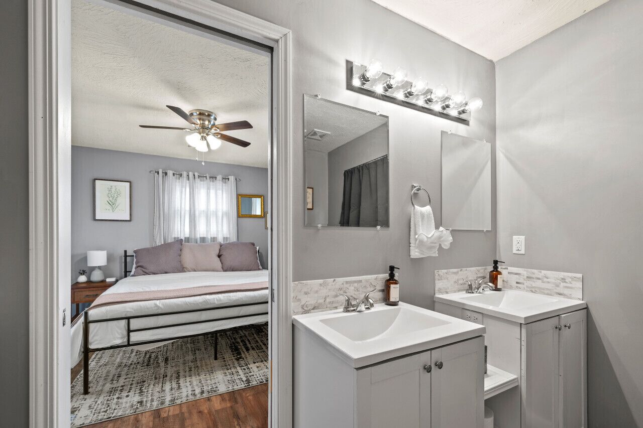 A bedroom with a bed, a ceiling fan, a nightstand, and a bedside table.