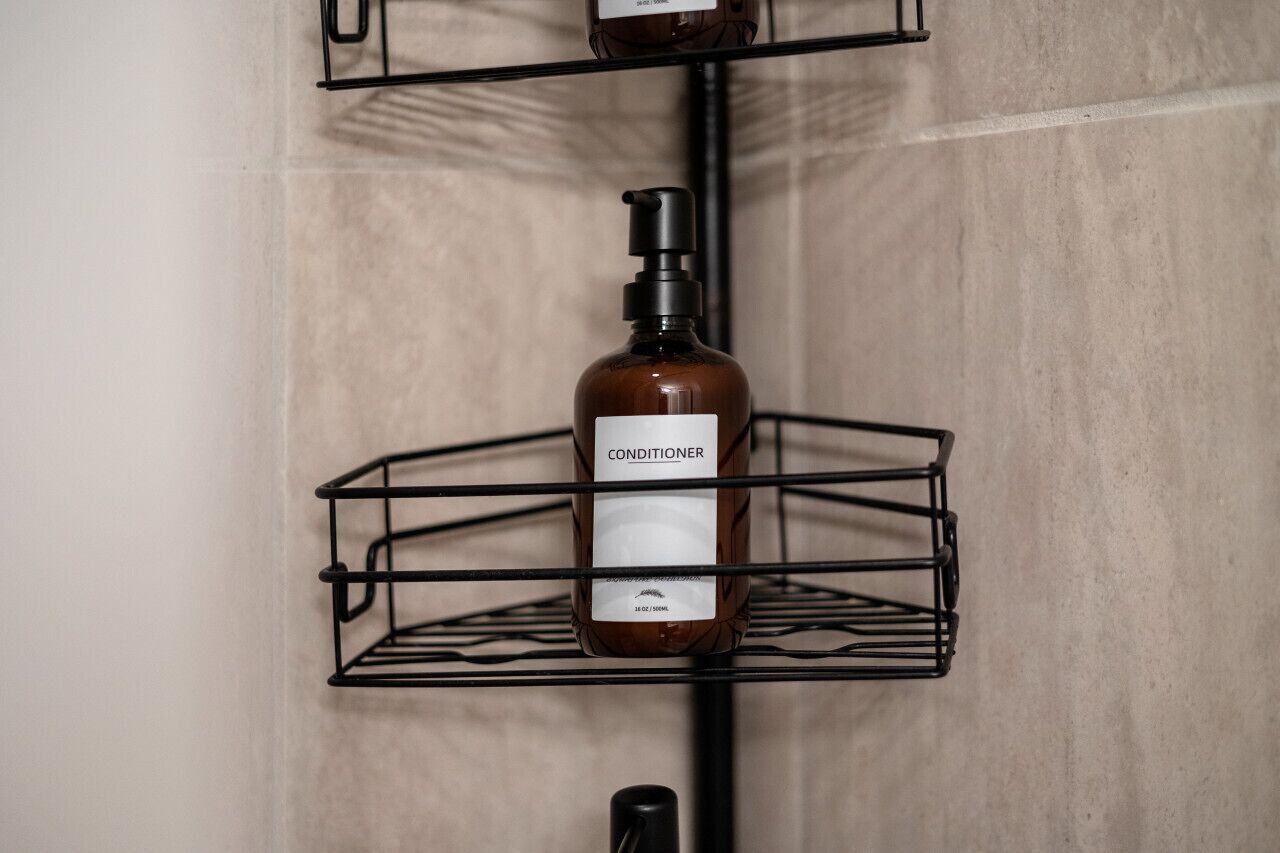 Una estantería en el baño con una botella de acondicionador.
