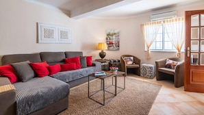 Un salon avec un canapé gris, des coussins rouges, une table basse et une lampe.