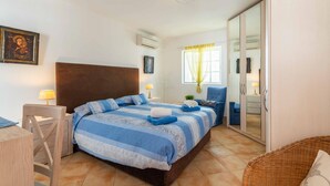 Une chambre à coucher avec un grand lit, une tête de lit en bois, une table de chevet avec une lampe, une chaise et une armoire avec un miroir.