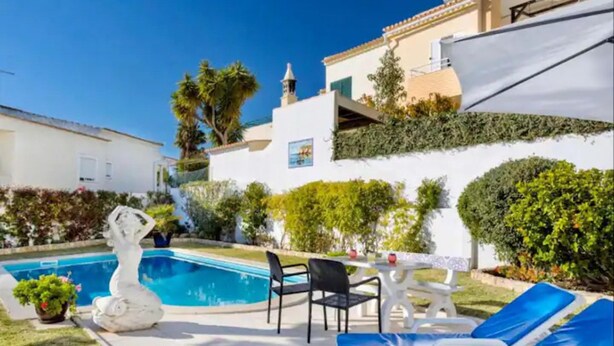Un espace aménagé au bord de la piscine, avec une statue, des chaises longues et une table.