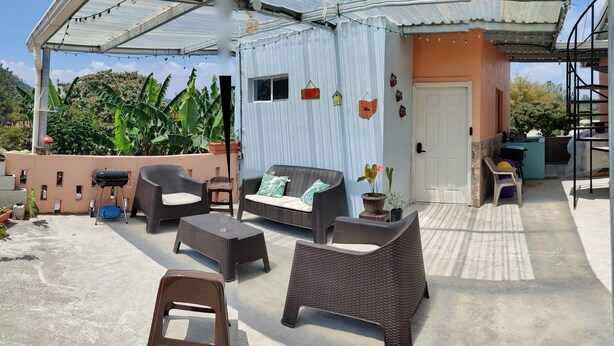 An outdoor patio with wicker furniture, a small stool, and a potted plant. - Cozy 1-bedroom guest house with WiFi, AC in fabulous Marcala (La Paz)
