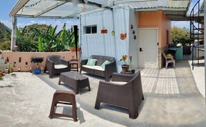An outdoor patio with wicker furniture, a small stool, and a potted plant. - Cozy 1-bedroom guest house with WiFi, AC in fabulous Marcala (La Paz)