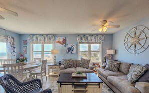 A living room with a sofa, coffee table, and a dining area with a table and chairs.