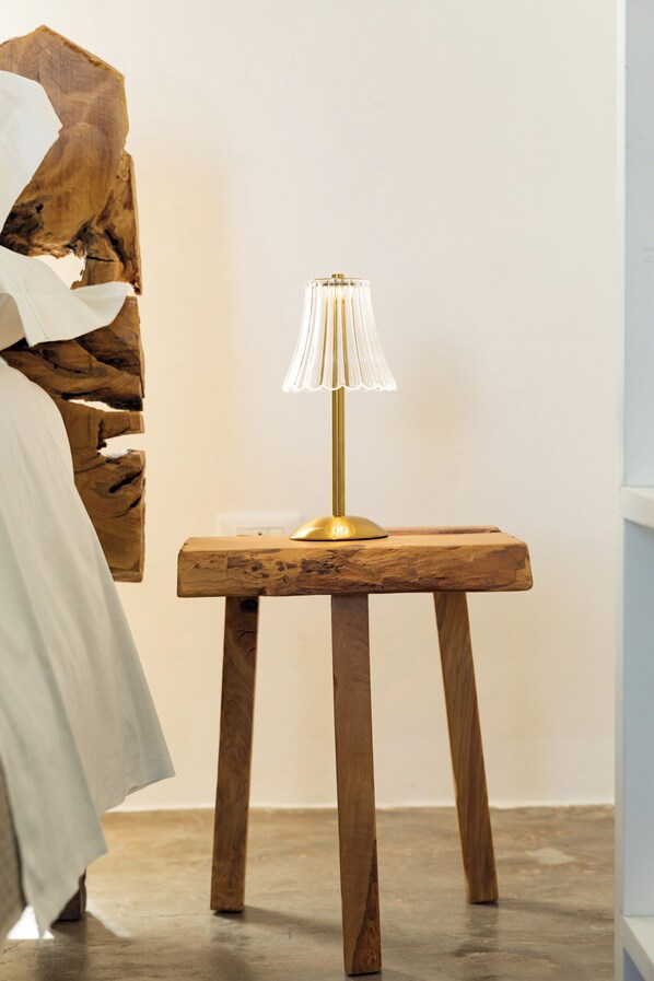 A wooden table with a gold lamp, a white wall, and a piece of abstract art. - Masseria Abadia Uno (Ostuni)