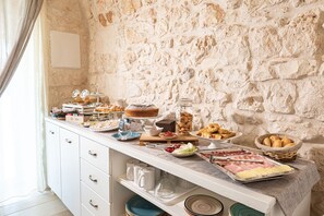 A buffet with various food items and a stone wall background.