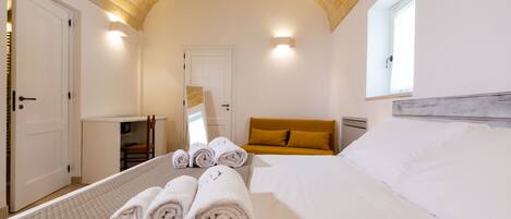 Habitación de hotel con cama, una mesita y una silla. Hay toallas en la cama y una ventana con vistas.
