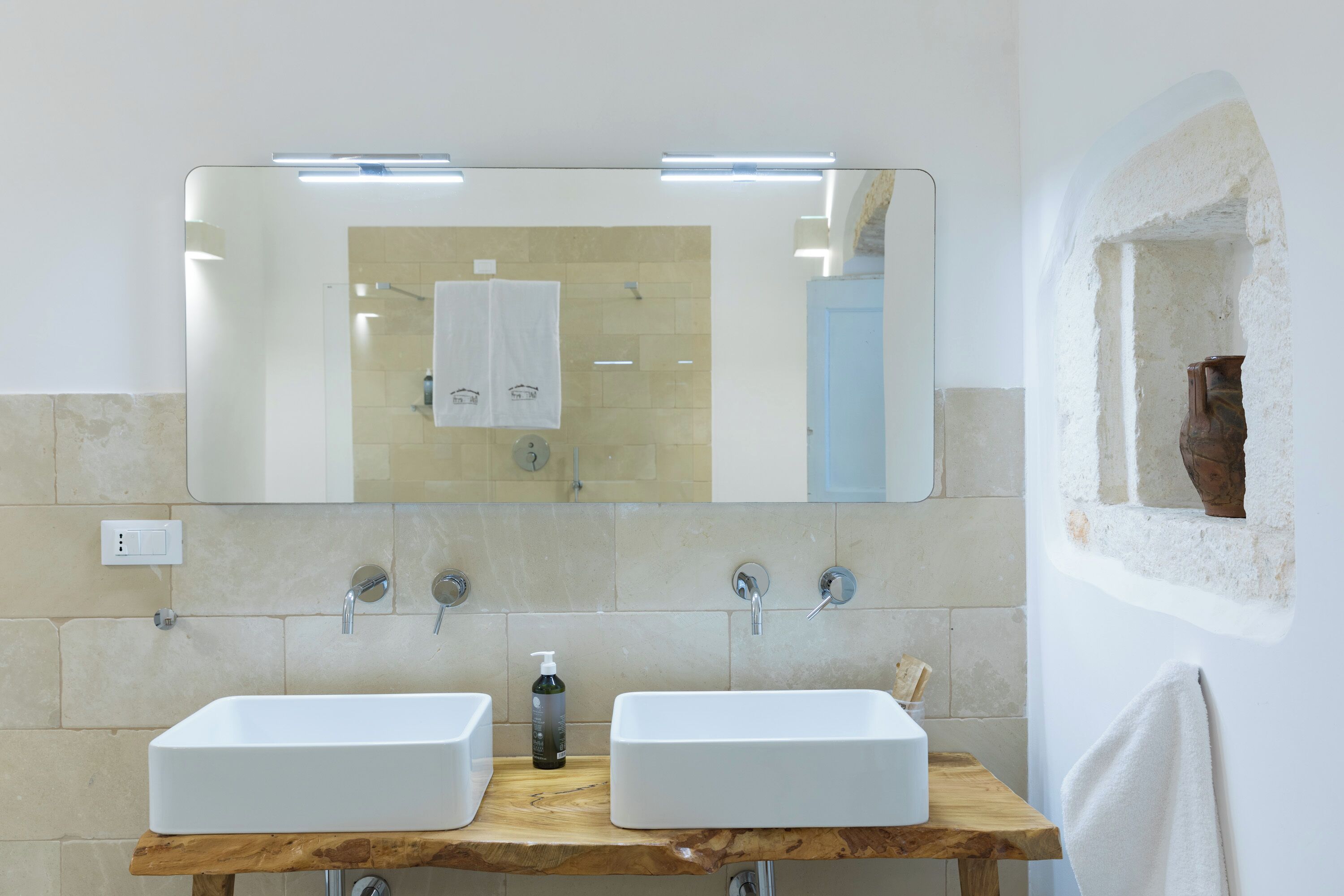 Un baño con dos lavamanos, un espejo y un mueble de tocador de madera.