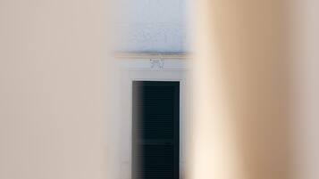 A narrow corridor with a door at the end, a sign above the door indicating a suite, and a textured wall above the door.