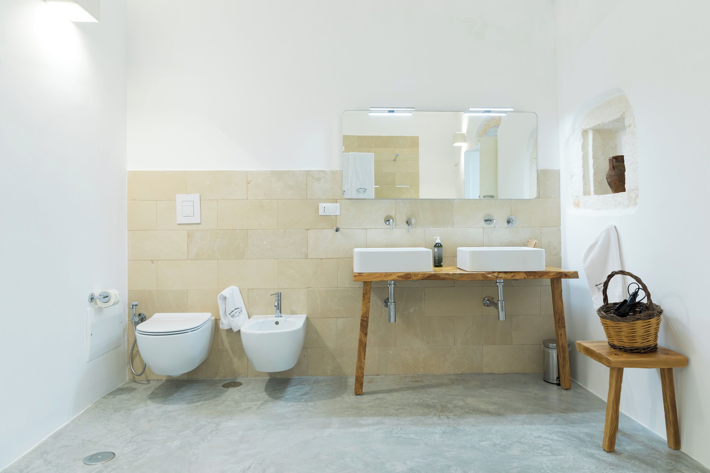 Une salle de bain moderne avec deux lavabos, un bidet et un meuble-lavabo en bois.