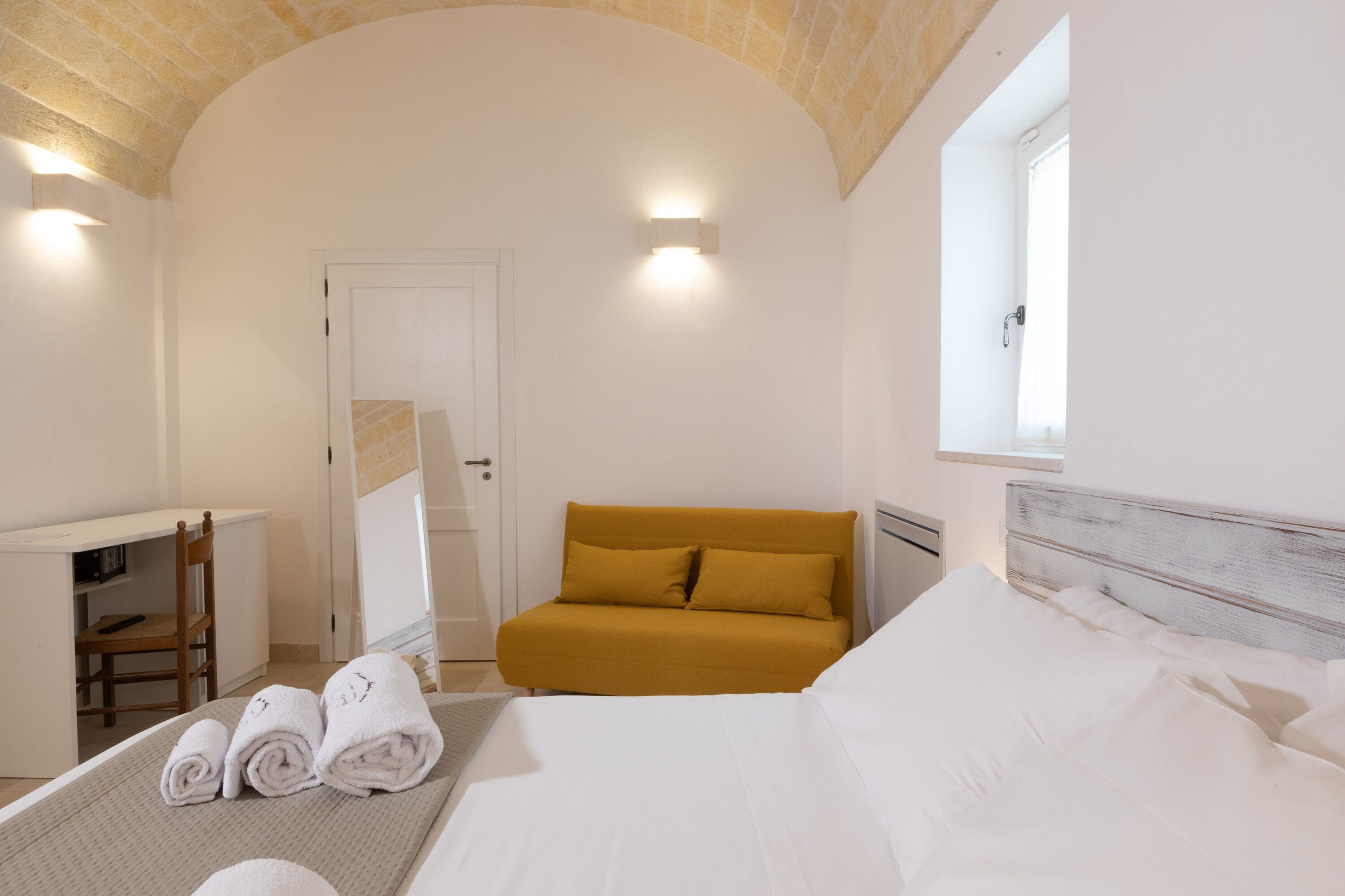 Ein Hotelzimmer mit Bett, Sofa, Schreibtisch und Stuhl.