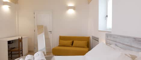 A hotel room with a bed, a sofa, a desk, and a chair.