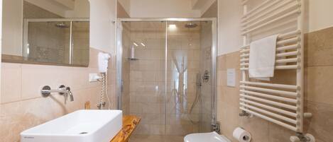 Ein modernes Badezimmer mit einer Glaskabine zur Dusche, einem hölzernen Waschtisch, einem weißen Waschbecken und einem Handtuchhalter.
