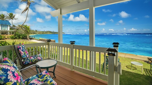 A covered outdoor area with a wooden deck, white railing, and a view of the ocean. - Summer Deal Oceanfront Kauai 2BR Home with Direct Beach Access (Anahola)