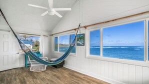 A room with a hammock, large windows, and a view of the ocean. - Summer Deal Oceanfront Kauai 2BR Home with Direct Beach Access (Anahola)