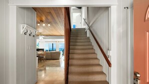 A staircase with a wooden handrail leading to a room with a view. - Summer Deal Oceanfront Kauai 2BR Home with Direct Beach Access (Anahola)