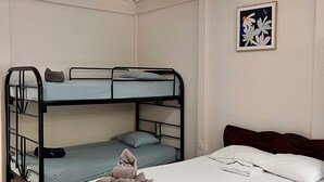 A room with a bunk bed, a single bed, and a framed picture on the wall. - Family Hotel (Cahuita)