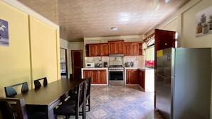 A compact kitchen with wooden cabinets, a refrigerator, a microwave, and a stove. - Family Hotel (Cahuita)