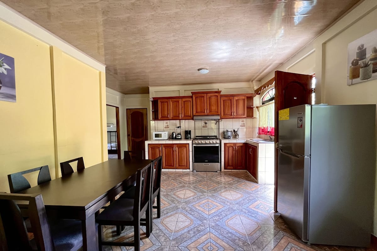 A compact kitchen with wooden cabinets, a refrigerator, a microwave, and a stove.