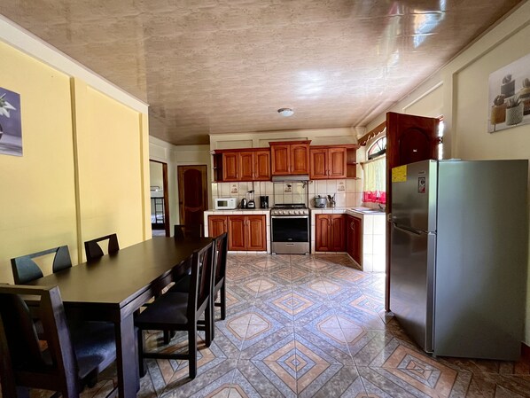 A compact kitchen with wooden cabinets, a refrigerator, a microwave, and a stove. - Family Hotel (Cahuita)