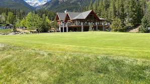 A lodge with a large lawn, wooden exterior, and mountain views. - Carsonland Getaways Panorama BC (Panorama)