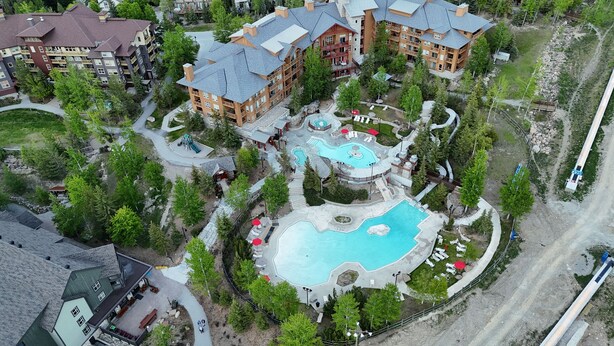 An aerial view of a resort with multiple buildings, a central pool area, and surrounding greenery. - Carsonland Getaways Panorama BC (Panorama)