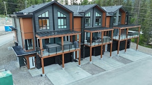 A modern multi-story house with a balcony on each floor, large windows, and a garage. - Carsonland Getaways Panorama BC (Panorama)