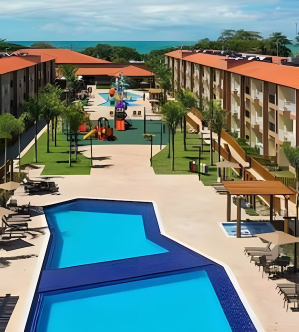 A resort with a central pool, outdoor seating, and a view of the ocean. - Ondas Praia Resort (Porto Seguro)
