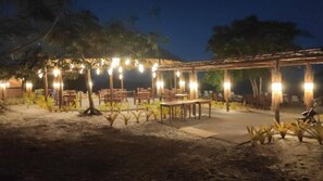 An outdoor dining area with tables and chairs under a pergola, surrounded by plants and trees. - Ondas Praia Resort (Porto Seguro)