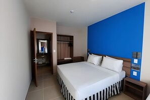 A hotel room with a large bed, a wardrobe, a mirror, and a blue accent wall. - Ondas Praia Resort (Porto Seguro)