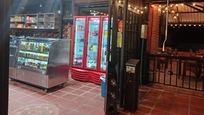A restaurant with a Coca-Cola refrigerator, a beverage cooler, and a speaker system.