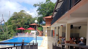 A pool area with a view of a building, a covered seating area, and a staircase leading to an upper level.