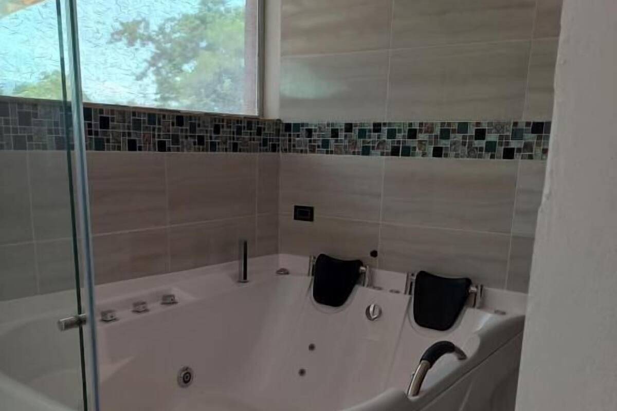 A modern bathroom with a large, curved bathtub, a glass shower enclosure, and a tiled backsplash with a mosaic design.