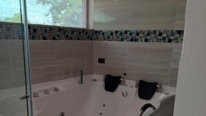 A modern bathroom with a large, curved bathtub, a glass shower enclosure, and a tiled backsplash with a mosaic design.
