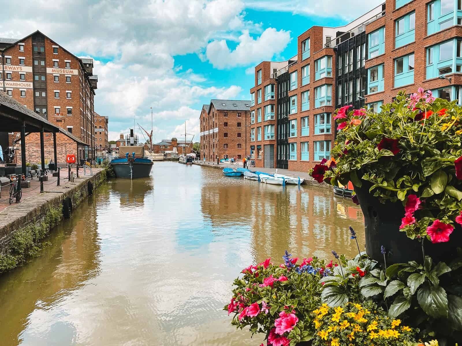 A canal with boats, buildings, and a flower pot.