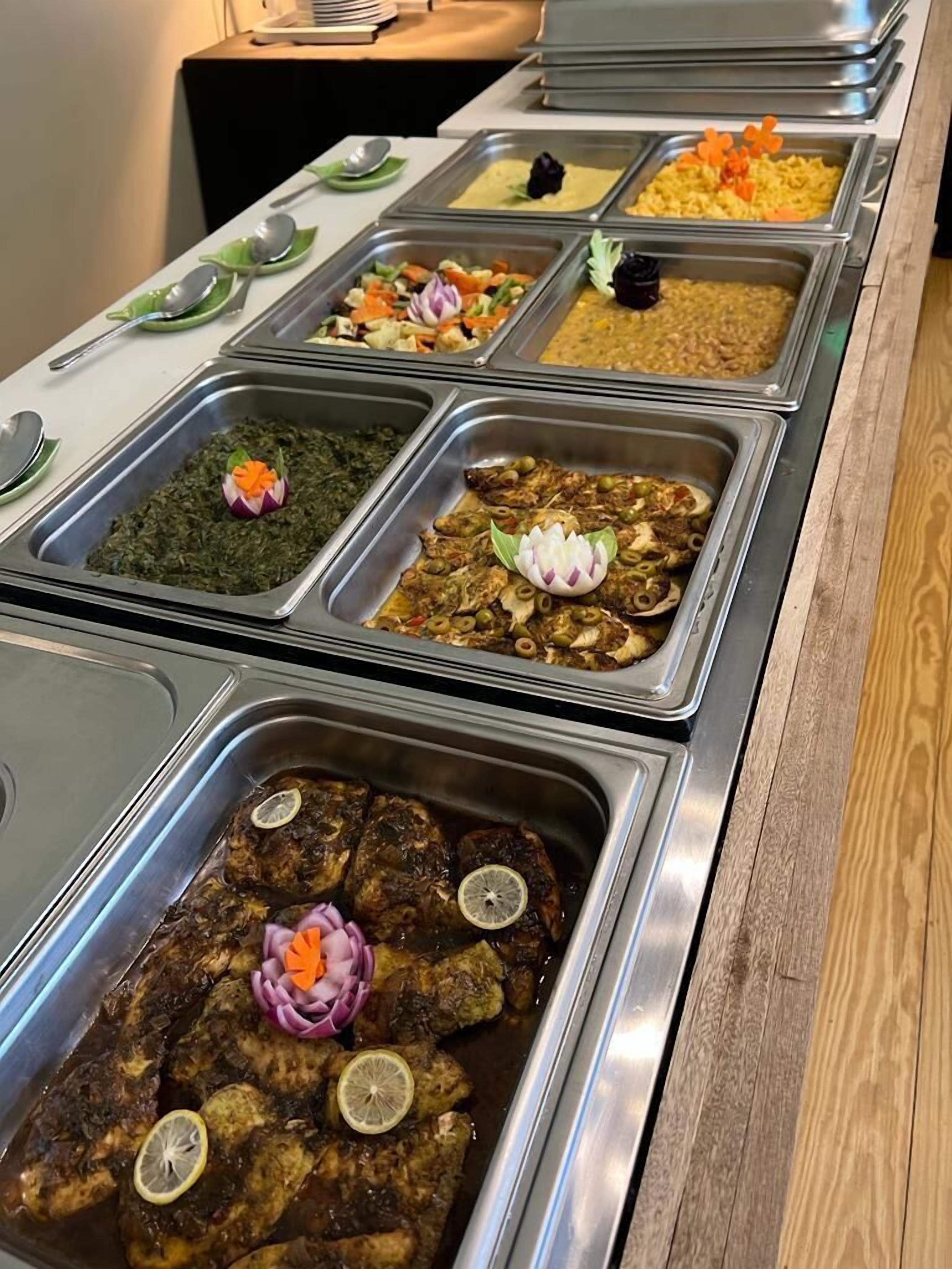A buffet with various dishes in metal containers, including a section with meat and vegetables.