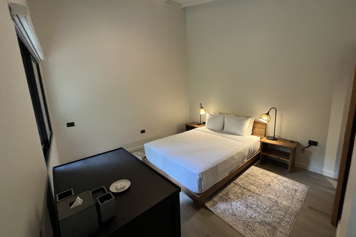 Une chambre à coucher avec un lit, des tables de chevet, un bureau et un tapis.