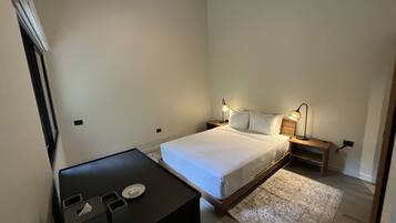 A bedroom with a bed, bedside tables, a desk, and a rug.