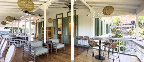 Un espace extérieur aménagé avec des meubles en osier, un sol en bois et des volets verts.