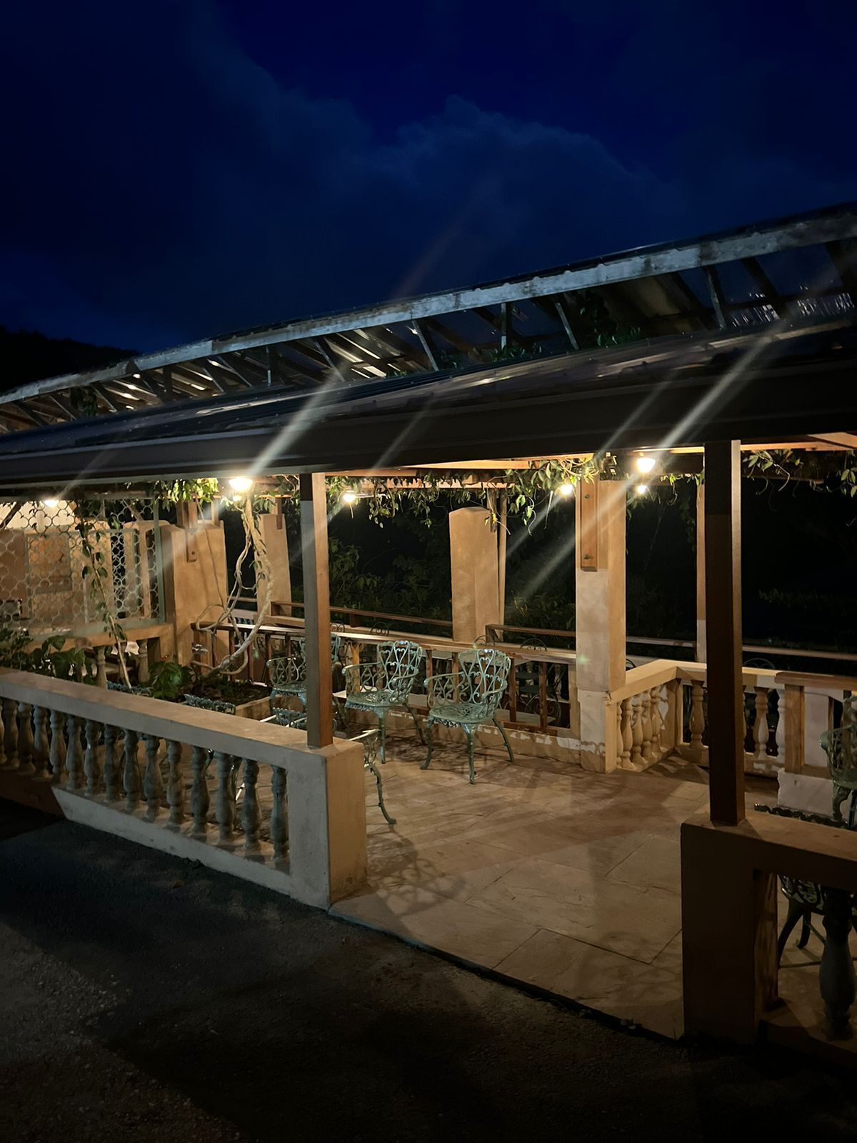 An outdoor patio area with a covered seating area, stone columns, and a railing.