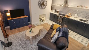 A modern living room with a TV, sofa, coffee table, and a decorative clock. - The Hare (Nantwich)