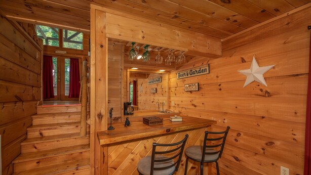 A wooden interior with a bar area, two bar stools, and a sign reading "Beer & Garden". - A Gatlinburg Game House For 6 (GATLINBURG)