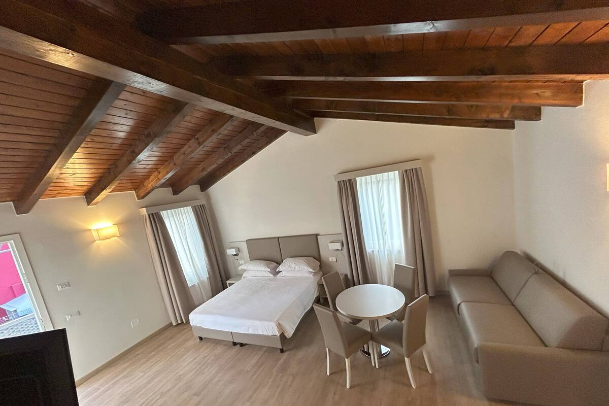 A room with a bed, a round table with chairs, and a sofa.