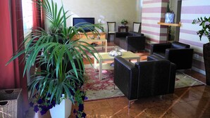 Una sala de estar con televisor, sofás, una mesa de centro y una planta grande en maceta.