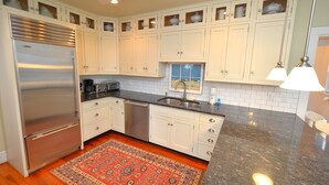 A kitchen with white cabinets, a stainless steel refrigerator, a dishwasher, and a granite countertop.