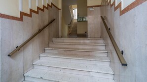 A staircase with beige walls and wooden handrails, leading to an upper floor. - Dora Apartment by Wonderful Italy (Turin)