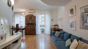 A living room with a blue sofa, wooden cabinet, and framed pictures on the wall. - Dora Apartment by Wonderful Italy (Turin)