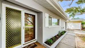 A residential house with a glass door, a small garden, and a tiled entrance. - Updated Clearwater Home, Close to Beaches & Pet Friendly!  (Clearwater)