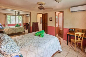 A hotel room with two beds, a desk, a chair, and an air conditioning unit. - Beachfront Apartment 1 Bedroom - Mariposa (Playa Tamarindo)